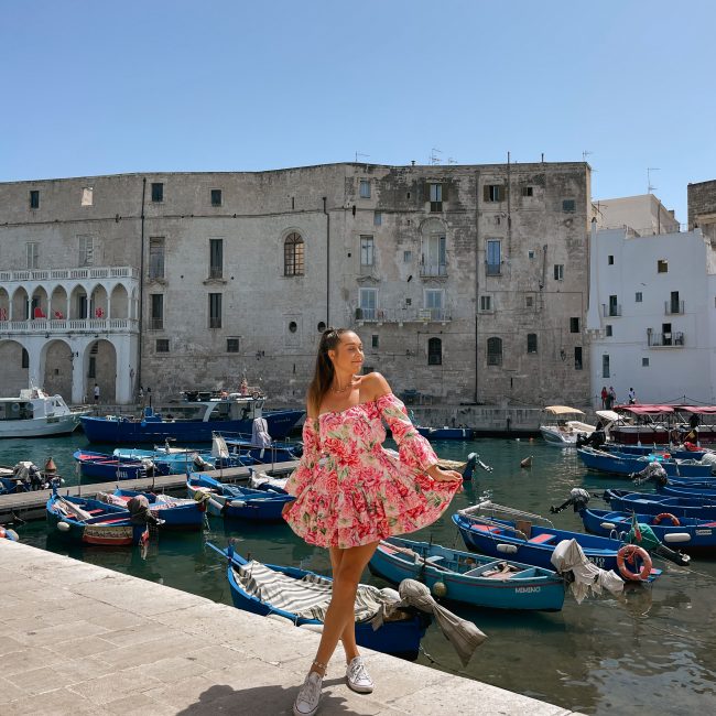 Girl with a flowery dress posing in the harbour in Monopoli, Puglia