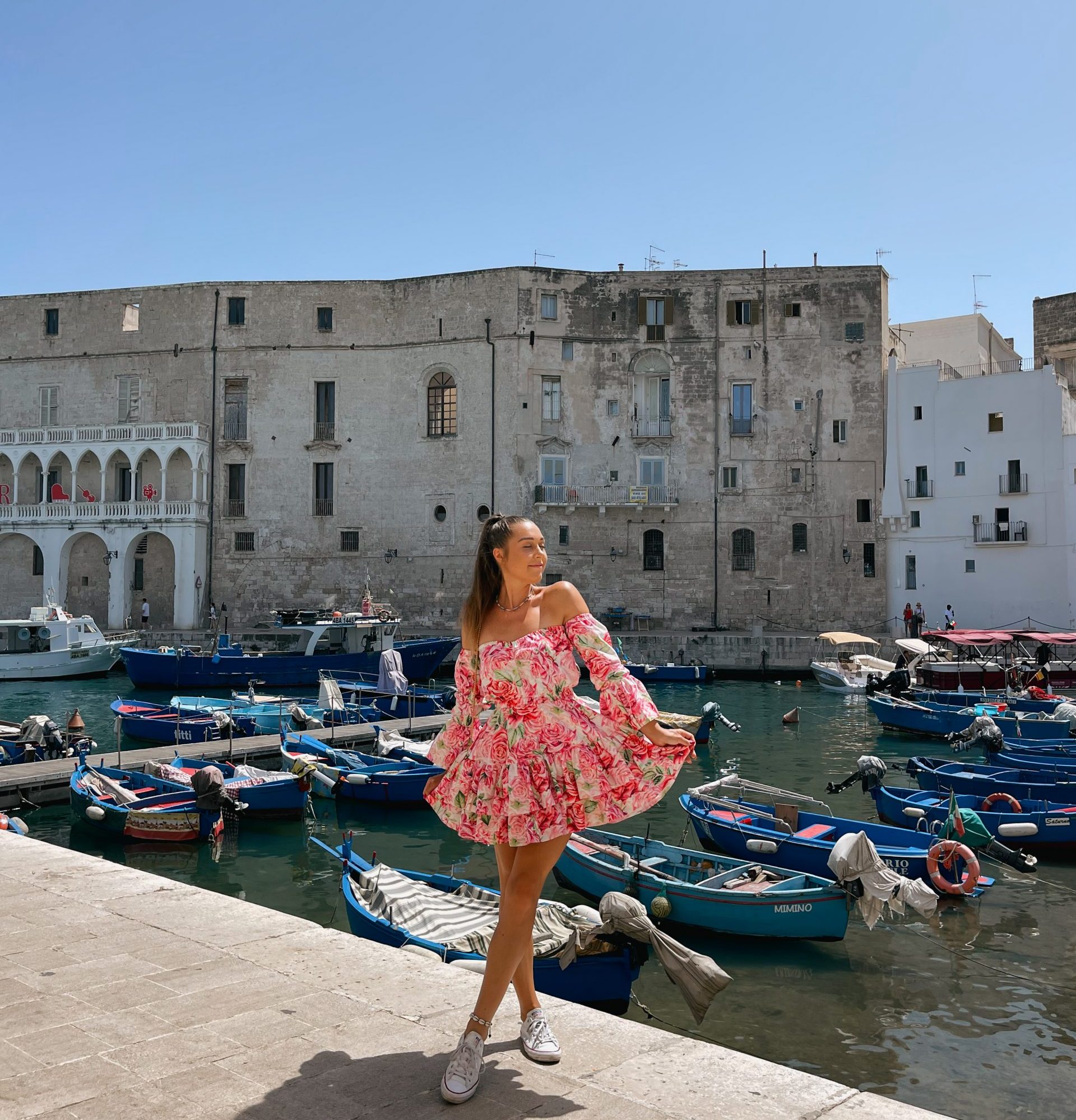 Girl with a flowery dress posing in the harbour in Monopoli, Puglia