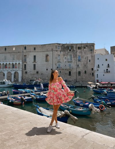 Girl with a flowery dress posing in the harbour in Monopoli, Puglia